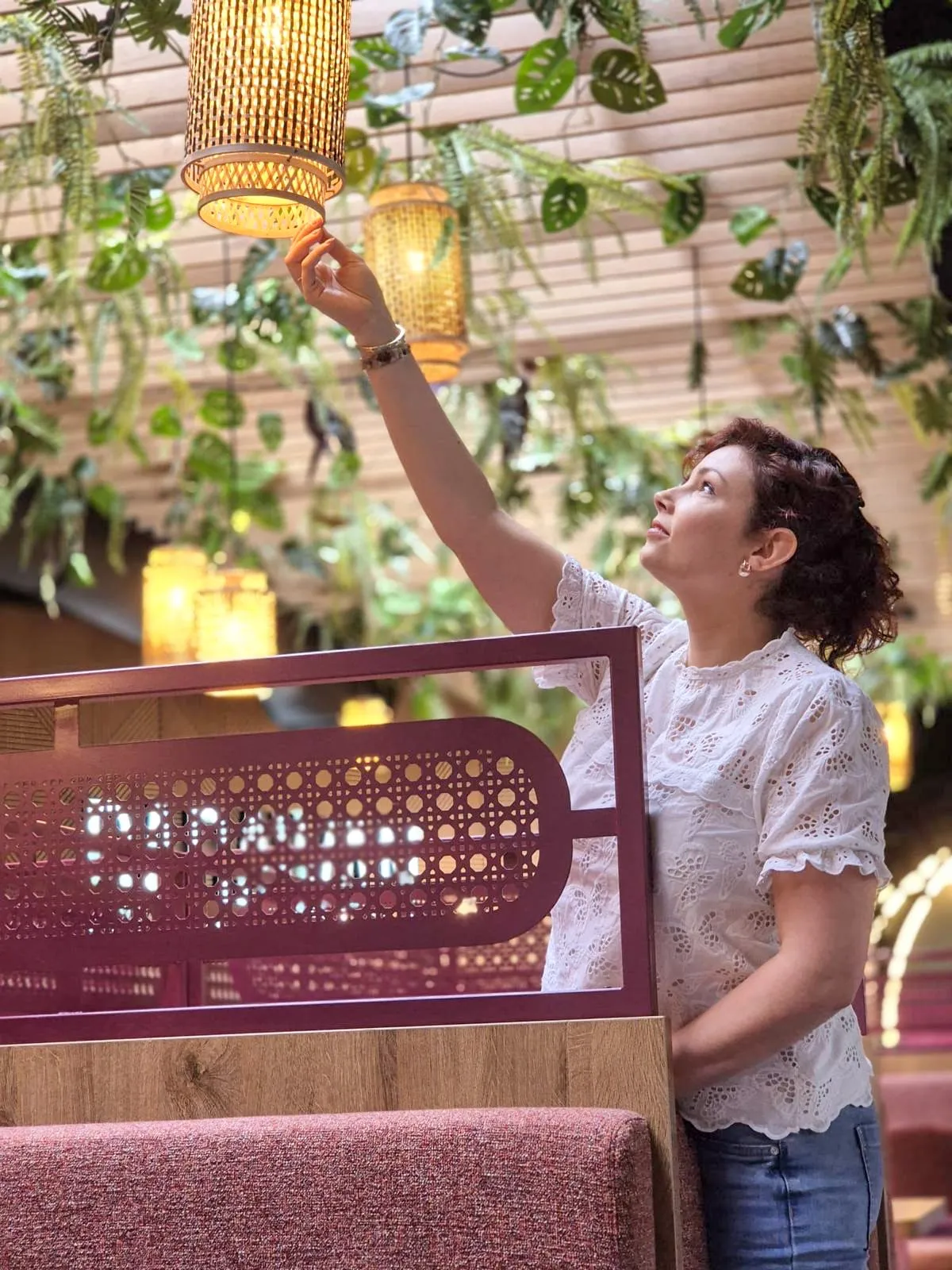 Stephanie Vissers stelt een rieten hanglamp af tussen de planten