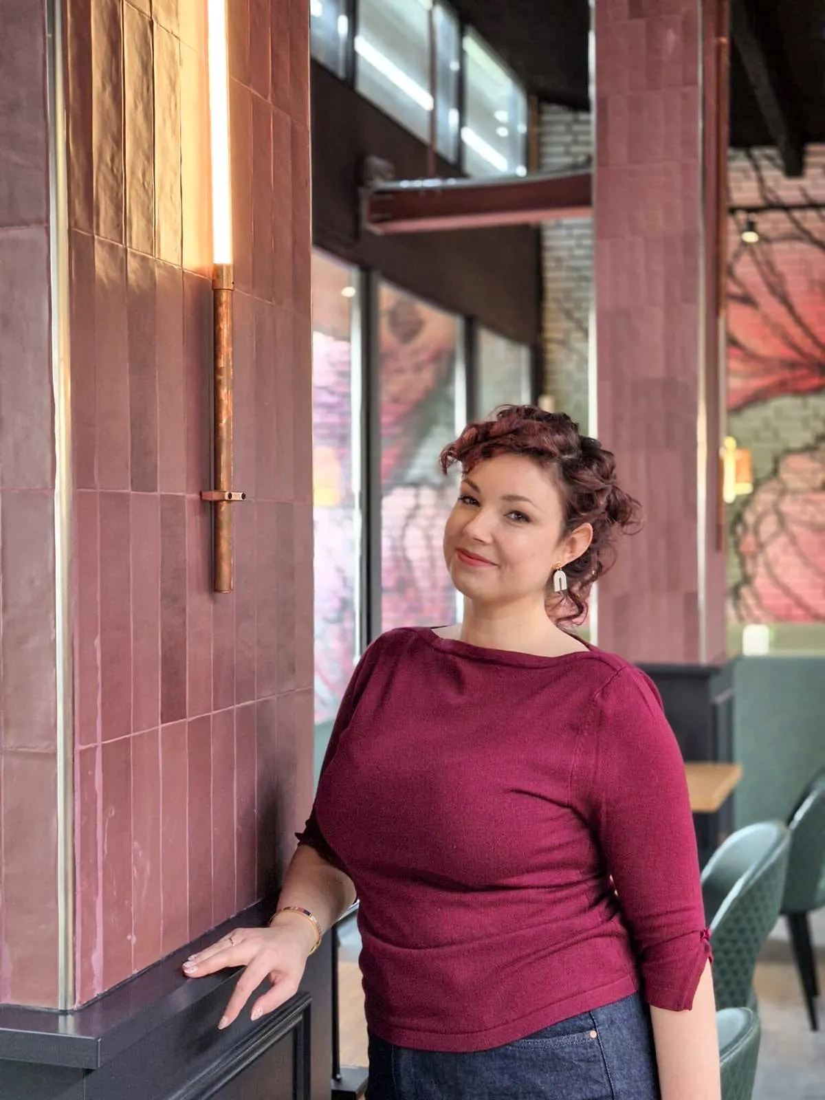 Stephanie Vissers in een restaurantinterieur met roze tegelwand